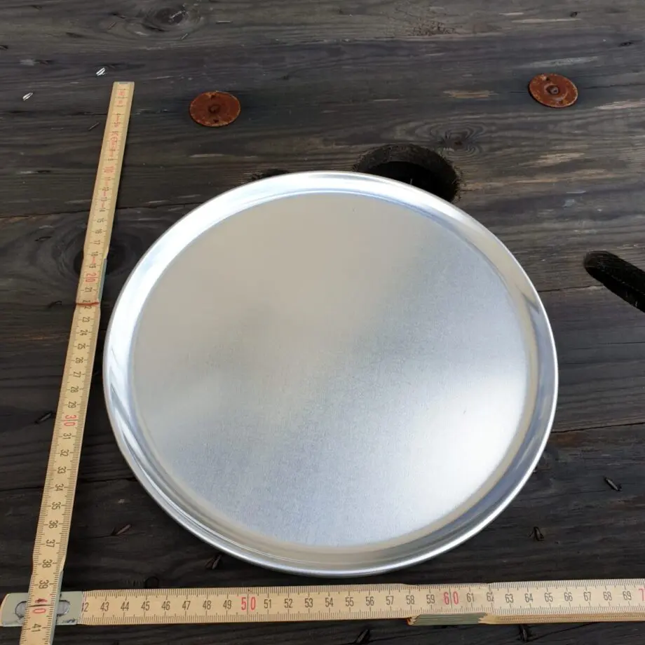 Tallrik 28 cm i aluminium / Runt Serveringsfat 28 cm diameter i obehandlad aluminium - grymt snygg servering av tapas Med denna rustika tallrik blir dukningen riktigt snygg. Du kan även använda tallriken som serveringsfat eller serveringsbricka för att snyggt duka fram allt från BBQ till skaldjur eller varför inte tapas och plockmat! Detta serveringsfat kan även användas för att varma upp mat på grillen, du skall dock vara medveten om att öppen låga på sikt kommer att sota ytan. Pizza blir krispig även vid en andra uppvärmning när du använder detta serveringsfat för uppvärmning i ugn eller grill.