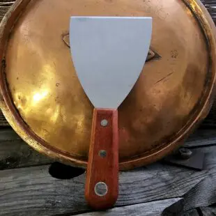 Stekbordsskrapa Snygg och rejäl stekbordsskrapa för kolstål mm. rengör enkelt stekbord och stekytor på din grill och i köket Stekbordsskrapa - så du kan lägga in spackelspaden i förrådet igen. Perfekt för rengöring av kolstålsstekbord. Stabil, vass och oumbärlig. Stekborsskrapan har en vass egg med en vinkel som gör att den håller sig vass även vid tufft arbete mot hårt underlag såsom kolstål eller gjutjärn. Handtaget är av äkta trä och har snygga nitar i rostfritt samt ett hål för upphängning på en spik eller krok.