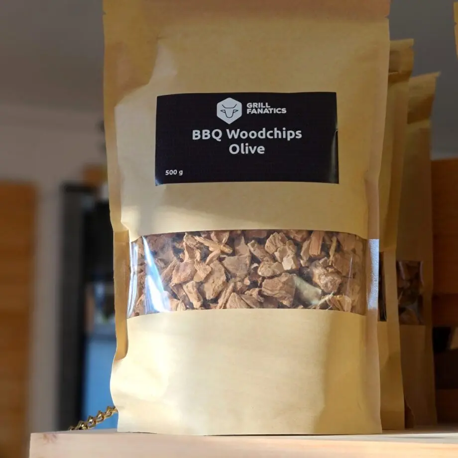 Rökflis - Oliv Wood chips av olivträ - karaktärsfull doft och rök  Rökflis, Wood chips, rökträ, rökved - det finns en del olika namn och än så länge verkar inte Svensken ha bestämt sig för vilket ord som ligger bäst på tungan. Hur som helst - vad vi alla är överens om är att det gör väldigt stor skillnad på smak och upplevelse genom att tillföra torrt trä till kolen, briketterna eller gasolbrännarna. Karaktär Detta är rökflis / wood chips av olivträ. Oliv ger en mycket speciell rök som för tankarna till en varm sommarkväll på en bakgata i medelhavsområdet, du går där och känner en söt och mysig rökdoft. Kvällen går sen ut på att leta upp stället som gör pizza eller grillar på torra grenar från olivträ - heeelt ljuvlig doft! Testa Olivträ till griskött, vego och till pizza - släng på en näve för att ge din pizza både extra hetta (torrt trä brinner hetare än kol) och en extra dimension vad gäller vedugnsbakat. Storleken har betydelse Den mindre storleken gör dessa woodchips / rökflis perfekta för kortare grill- BBQ- och röksessioner som kräver en kraftfull rökutveckling på kort tid (små träbitar börjar snabbare pyra och producera rök än större bitar). Det är även lämpligt att testa använda flis i täta grillar som kamadogrillar  eftersom att dessa rökgrillar har så lågt flöde av luft att du mycket väl kan nå bättre rökresultat med flis som en del av ditt rökträ. Torr är bäst Även om många ger rådet att lägga flis i blöt före användning vill BBQmonster ge dig rådet att testa lägga torrt trä intill glöden och på så sätt skapa en miljö där frisk rök kan tillföras utan att flisen brinner upp. Har du en gasolgrill är du dock mer hjälpt av dessa mindre bitar trä - lägg dem i ugnsfolie, vik ihop och perforera med några hål, placera därefter över brännarna. Om att använda trä för att skapa rök: Blött trä släcker delvis glöden från kolen och skapar oftast en smutsigare rök. Målet när du tillför rökträ är att skapa en god förbränning där röken är klar och fin, inte tjock och mullrande. Röken skall lukta gott och blött trä luktar...inte gott. Thin blue smoke pratar det stora landet i väster om och även om det inte alltid är blå rök som lämnar skorstenen så kan du ha det i bakhuvudet: mörk rök är dåligt, vit rök är bättre men inte bra, ljus eller blåskimrande rök är frisk rök och ger bäst smak och doft. Om du upplever att röken inte är ljus kan du testa att öppna spjällen något mer och på så sätt förbättra förbränningen. Var dock noggrann med att se till att temperaturen inte rusar iväg. Kom ihåg: Torrt trä Lägg så nära glöden att rök börjar produceras Lukta på röken (använd bara trä som du gillar doften av) Se på röken (den skall vara så ljus som möjligt) Om röken är mörk, släpp in mer luft, skapa bättre drag Innehåller 500 gram av bästa, renaste trä (utan bark) levererat i en stand up bag av papp.