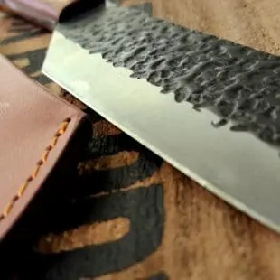 BBQ-kniv Kockkniv BBQmonster - robust kniv/cleaver med slida i läder. 5mm grov rygg och en vikt på 400 gram En bbq-kniv för BBQ och Grillning: BBQmonster BBQ-kniv / cleaver är kniven som är en kombination av en rejäl kockkniv och en Cleaver / köttyxa, och med denna i din hand är inte en kotlettrad eller ett revbensspjäll säkert någonstans. Bladet är EXTREMT stabilt och viker inte även vid hårdare tag. Ryggen är hela 5mm tjockt och större delen av bladet har en härlig hammrad yta som kniven rejält "intstagramvänlig" och photogenique. Denna BBQkniv kommer en slida av läder vilket gör att du kan bära den i din livrem eller i ditt förkläde. Skaftet är av polerat och lackat hårdträ och detta omsluter det genomgående knivbladet avslutning. Skaftet ger ett bra grepp och är enkelt att rengöra. Handtaget passar både höger- och vänsterhänta. Kolstål med blandning X50CrMoV15 Hårdhet 56° HRC vilket är ett relativt mjukt stål - något som gör att du själv enkelt kan hålla din kniv vass. Total längd: 29 cm Längd på bladet: 18 cm Längd på skaftet: 11 cm