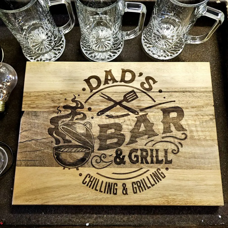 Skärbräda "Dad´s BBQ" by BBQmonster dubbla sidor med unika motiv - Valnötsträ från Europa. Tapas på sida 1 och skärbräda på sida 2 Optimala presenten på farsdag eller julklappen till Grillpappan no1 Här har du den - den perfekta farsdagspresenten! Ett hantverk där brädan av europeisk Valnötsträ har handslipats och oljats i Sverige. Varje bräda är unik, där mörkare och ljusare trä har kombinerats. Vi har 10st exemplar att sälja med dessa motiv - så säkra ditt exemplar redan idag och ge dig själv eller någon du gillar en inredningspryl som bara blir snyggare för varje år. På ena sidan har du en slät yta och blodränna samt BBQmonsters logo "Make BBQ great again" inbränd i övre högra hörnet. Om du flippar den ett varv så har du en sida med ett mäktigt vackert designelement inbränt: "Dad´s Bar & Grill, Chilling & Grilling" Måtten på denna skärbräda / tapas bricka Bredd: 390 mm Höjd: 285mm Tjocklek: 20mm Träet är oljat med naturlig vegetabilisk olja för att förhindra sprickbildning. Torka av ytan noggrant med en trasa doppad i ljummet vatten och torka torrt. För att underhålla träet kan du använda en olja för köksbänkar av trä eller helt enkelt en ren olivolja. Träet kommer att mörkna något efter varje behandling.