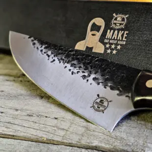 BBQ-kniv / kockkniv "Smith #9" 30cm - kolstål med med snyggt hamrat blad - galet vass och vackert handtag av ädelträ - säljs för det tredubbla på andra sidor! Söker du en serie av välarbetade och lättskötta kockknivar? Ta en kik på BBQmonsters egna serie knivar! Samtliga knivar i serien kommer i en svart presentförpackning med BBQmonsters sigill "Make BBQ great again" tryckt på locket. Knivarna från BBQmonster har även BBQmonsters logo ingraverad på bladet. Vi sätter bara vår logo på prylar som vi verkligen tycker om - detta är en sådan. Introduktionspris - passa på! En perfekt till grillnörden, en present till pappa på farsdag eller till dig själv helt enkelt! Denna modell av kökskniv är lämplig allround kniv i uteköket eller köket. Kniven kan användas till det mesta i köket då eggen är tillräckligt lång för att nå tvärs över de flesta bitar kött.  Bladet på denna Smith #9 är otroligt vasst, stabilt, lättskött och bladet har en härlig hamrad svart yta. Tillsammans allts som allt gör detta kniven rejält "intstagramvänlig" och photogenique. På ovansidan av bladet sitter en ölöppnare så du slipper slita på snusdosan. (Vill du hellre ha en ölöppnare uppskruvad på väggen så ta en kik på denna Bulldog i gjutjärn!) Bladet är genomgående och avslutas med handtaget som är av polerat och lackat ädelträ och fyra nitar av mässing. Skaftet ger ett skönt grepp och är enkelt att rengöra. Handtaget passar både höger- och vänsterhänta. Kolstål med blandning X50CrMoV15 Hårdhet 56° HRC vilket är ett relativt mjukt stål - något som gör att du själv enkelt kan hålla din kniv vass. Total längd: 32 cm Längd på bladet: 20 cm Längd på skaftet: 12 cm Vikt: 280 gram