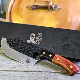 Kökskniv / Funktionskniv "Trigger #8" 29cm - grovt kolstål med med snyggt hamrat blad och galet vass - plats för pekfingret i bladet för mer kraft - säljs för det tredubbla på andra sidor! Söker du en serie av välarbetade och lättskötta kockknivar? Ta en kik på BBQmonsters egna serie knivar! Samtliga knivar i serien kommer i en svart presentförpackning med BBQmonsters sigill "Make BBQ great again" tryckt på locket. Knivarna från BBQmonster har även BBQmonsters logo ingraverad på bladet. Vi sätter bara vår logo på prylar som vi verkligen tycker om - detta är en sådan. Introduktionspris - passa på! En perfekt till grillnörden, en present till pappa på farsdag eller till dig själv helt enkelt! Denna modell av kökskniv är av typen som bäst beskrivs som en funktionskniv. Kniven kan användas till det mesta i köket men även en bra kompis på äventyret i vildmarken.  Att typen av kniv blivit populär beror sannolikt på hålet i bladet som ger dig en naturlig plats att placera ditt pekfinger, detta för mer kraft och bättre känsla att styra kniven även vid precisionsjobb. Bladet på denna Trigger #8 är grovt,  stabilt, lättskött och bladet har en härlig hamrad svart yta. Tillsammans allts som allt gör detta kniven rejält "intstagramvänlig" och photogenique. På ovansidan av bladet sitter en ölöppnare så du slipper slita på snusdosan. (Vill du hellre ha en ölöppnare uppskruvad på väggen så ta en kik på denna Bulldog i gjutjärn!) Bladet är genomgående och avslutas med handtaget som är av polerat och lackat ädelträ och tre nitar av mässing. Skaftet ger ett skönt grepp och är enkelt att rengöra. Handtaget passar både höger- och vänsterhänta. Kolstål med blandning X50CrMoV15 Hårdhet 56° HRC vilket är ett relativt mjukt stål - något som gör att du själv enkelt kan hålla din kniv vass. Total längd: 29 cm Längd på bladet: 17 cm Längd på skaftet: 12 cm Vikt: 300 gram