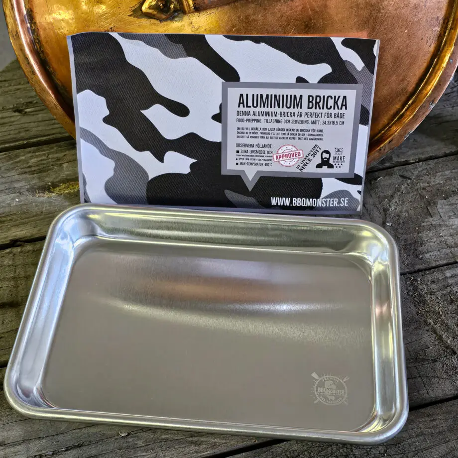 Mini BBQ Tallrik Aluminium Plate 24*16*2,6cm Bricka - metalltallrik för servering - perfekt för burgare - Två stycken av denna ryms i den en storlek större alu-tallriken En ruggigt robust "mini" BBQ Alu tallrik - en kvalitet som du inte sett innan! BBQmonster skulle vilja påstå att detta är marknadens mest stabila och robusta BBQ tallrik, som också passar perfekt som serveringsbricka för exempelvis burgare. Brickan har BBQmonsters logo diskret lasergraverad i ena hörnet. BBQmonster sätter bara sin sigill på prylar som håller måttet och där det kan sägas med stolthet att det är pryl värdig Foodies och Grillers med krav - denna BBQ Alu bricka är en sådan pryl. Grymt snygg och praktisk "mini-tallrik" i obehandlad Aluminium. Skapar den rustika BBQ, grill och Steakhouse-känslan. Blir bara snyggare med tiden med de repor som uppkommer vid användning. Komplettera med några snygga grillknivar och du har en riktigt cool dukning inom räckhåll. Tålig och enkel att rengöra. Fungerar även perfekt som uppläggningsfat och smidigt när du rubbar en mindre köttbit. Tips: Vill du behålla den i blank aluminium-finish så handdiskar du den, vill du den skall få ett utseende likt "tenn" så kör du den i diskmaskin upprepade gånger (obs - den går efter det ej att "återställa" till originalskick). Vill du göra rengöringen ännu enklare och dukningen ännu mer cool så lägger du slaktarpapper som underlag. Mått: 24cm * 16,5 cm  episkt snygg hygienisk och lättrengjord tål upp till 400 grader C Se även de två större brickorna i samma kvalitet: Medium (tallriksmodellen för de flesta) Large (kylskåpsanpassad och passa de flesta ugnar!) XL (perfekt för som underlag vid köttpreparering eller som bricka för att servera från. Om du skall hantera tallriken direkt från Grillen så tänk på att skydda tassarna! https://bbqmonster.se/produkt/grillvantar-bbq-gloves-varmetaliga-handskar/ Se övriga BBQmonster sigillprodukter https://bbqmonster.se/produkt-kategori/bbqmonster-branded-products/