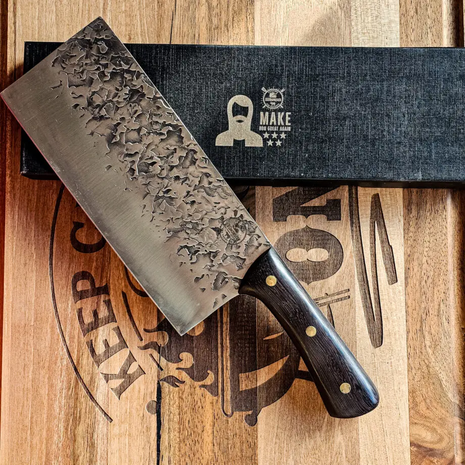 Chukabocho Kockkniv Black Ebony #3 Vacker kockkniv från BBQmonster serie av Asiatiska kockknivar - liknande kniv säljs för det tredubbla på andra sidor! Söker du en serie av välarbetade och lättskötta kockknivar? Ta en kik på BBQmonsters egna serie knivar! Samtliga knivar i serien kommer i en svart presentförpackning med BBQmonsters sigill "Make BBQ great again" tryckt på locket. Knivarna från BBQmonster har även BBQmonsters logo ingraverad på bladet. Vi sätter bara vår logo på prylar som vi verkligen tycker om - detta är en sådan. Introduktionspris - passa på! En perfekt till grillnörden, en present till pappa på farsdag eller till dig själv helt enkelt! Denna modell av kökskniv är av typen Chukabocho fast slipad som en vanlig kniv. Detta är en kniv som företrädesvis används som rotfrukts- och grönsakskniv vilket man kan förstå då denna kniv är att den perfekt när du skall skapa snittytor som är jämntjocka, detta då bladet är imponerande 10cm högt. Samtidigt är eggen så pass rejäl och vass att du utan problem både kan hacka kött och hugga av brosket mellan två kotletter eller ribs. Att typen av kniv blivit populär beror sannolikt också på den smidiga hantering att plocka upp hackad lök, koriander och annat med ETT svep - bladet är som "skyffel". Bladet på denna Black Ebony #3 är smidigt, tunt, extremt vasst, lättskött. Varje blad är unikt i sitt utseende med en snygg textur inhamrat i stålet. Tillsammans allts som allt gör detta kniven rejält "intstagramvänlig" och photogenique. Bladet är genomgående och avslutas med handtaget som är av polerat och svart ädelträ och tre nitar av mässing. Skaftet ger ett skönt grepp och är enkelt att rengöra. Handtaget passar både höger- och vänsterhänta. Kolstål med blandning X50CrMoV15 Hårdhet 56° HRC vilket är ett relativt mjukt stål - något som gör att du själv enkelt kan hålla din kniv vass. Total längd: 33 cm Längd på bladet: 21 cm Längd på skaftet: 12cm Vikt: 414 gram