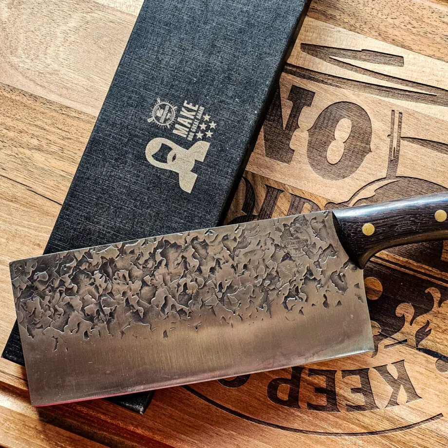 Chukabocho Kockkniv Black Ebony #3 Vacker kockkniv från BBQmonster serie av Asiatiska kockknivar - liknande kniv säljs för det tredubbla på andra sidor! Söker du en serie av välarbetade och lättskötta kockknivar? Ta en kik på BBQmonsters egna serie knivar! Samtliga knivar i serien kommer i en svart presentförpackning med BBQmonsters sigill "Make BBQ great again" tryckt på locket. Knivarna från BBQmonster har även BBQmonsters logo ingraverad på bladet. Vi sätter bara vår logo på prylar som vi verkligen tycker om - detta är en sådan. Introduktionspris - passa på! En perfekt till grillnörden, en present till pappa på farsdag eller till dig själv helt enkelt! Denna modell av kökskniv är av typen Chukabocho fast slipad som en vanlig kniv. Detta är en kniv som företrädesvis används som rotfrukts- och grönsakskniv vilket man kan förstå då denna kniv är att den perfekt när du skall skapa snittytor som är jämntjocka, detta då bladet är imponerande 10cm högt. Samtidigt är eggen så pass rejäl och vass att du utan problem både kan hacka kött och hugga av brosket mellan två kotletter eller ribs. Att typen av kniv blivit populär beror sannolikt också på den smidiga hantering att plocka upp hackad lök, koriander och annat med ETT svep - bladet är som "skyffel". Bladet på denna Black Ebony #3 är smidigt, tunt, extremt vasst, lättskött. Varje blad är unikt i sitt utseende med en snygg textur inhamrat i stålet. Tillsammans allts som allt gör detta kniven rejält "intstagramvänlig" och photogenique. Bladet är genomgående och avslutas med handtaget som är av polerat och svart ädelträ och tre nitar av mässing. Skaftet ger ett skönt grepp och är enkelt att rengöra. Handtaget passar både höger- och vänsterhänta. Kolstål med blandning X50CrMoV15 Hårdhet 56° HRC vilket är ett relativt mjukt stål - något som gör att du själv enkelt kan hålla din kniv vass. Total längd: 33 cm Längd på bladet: 21 cm Längd på skaftet: 12cm Vikt: 414 gram