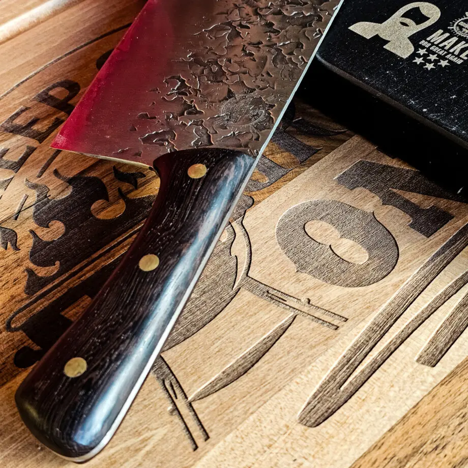 Chukabocho Kockkniv Black Ebony #3 Vacker kockkniv från BBQmonster serie av Asiatiska kockknivar - liknande kniv säljs för det tredubbla på andra sidor! Söker du en serie av välarbetade och lättskötta kockknivar? Ta en kik på BBQmonsters egna serie knivar! Samtliga knivar i serien kommer i en svart presentförpackning med BBQmonsters sigill "Make BBQ great again" tryckt på locket. Knivarna från BBQmonster har även BBQmonsters logo ingraverad på bladet. Vi sätter bara vår logo på prylar som vi verkligen tycker om - detta är en sådan. Introduktionspris - passa på! En perfekt till grillnörden, en present till pappa på farsdag eller till dig själv helt enkelt! Denna modell av kökskniv är av typen Chukabocho fast slipad som en vanlig kniv. Detta är en kniv som företrädesvis används som rotfrukts- och grönsakskniv vilket man kan förstå då denna kniv är att den perfekt när du skall skapa snittytor som är jämntjocka, detta då bladet är imponerande 10cm högt. Samtidigt är eggen så pass rejäl och vass att du utan problem både kan hacka kött och hugga av brosket mellan två kotletter eller ribs. Att typen av kniv blivit populär beror sannolikt också på den smidiga hantering att plocka upp hackad lök, koriander och annat med ETT svep - bladet är som "skyffel". Bladet på denna Black Ebony #3 är smidigt, tunt, extremt vasst, lättskött. Varje blad är unikt i sitt utseende med en snygg textur inhamrat i stålet. Tillsammans allts som allt gör detta kniven rejält "intstagramvänlig" och photogenique. Bladet är genomgående och avslutas med handtaget som är av polerat och svart ädelträ och tre nitar av mässing. Skaftet ger ett skönt grepp och är enkelt att rengöra. Handtaget passar både höger- och vänsterhänta. Kolstål med blandning X50CrMoV15 Hårdhet 56° HRC vilket är ett relativt mjukt stål - något som gör att du själv enkelt kan hålla din kniv vass. Total längd: 33 cm Längd på bladet: 21 cm Längd på skaftet: 12cm Vikt: 414 gram
