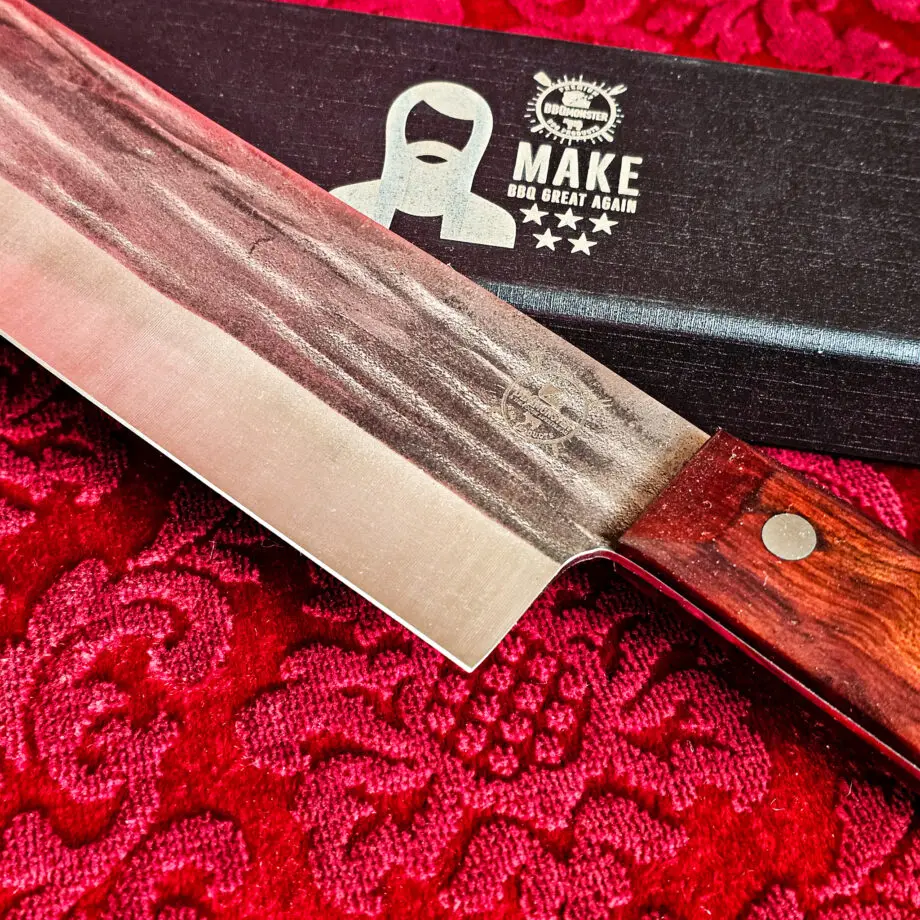 Nakiri Kockkniv Red Velvet #15 vacker kniv från BBQmonsters serie av Asiatiska kockknivar - liknande kniv säljs för det tredubbla på andra sidor! Söker du en serie av välarbetade och lättskötta kockknivar? Ta en kik på BBQmonsters egna serie knivar! Samtliga knivar i serien kommer i en svart presentförpackning med BBQmonsters sigill "Make BBQ great again" tryckt på locket. Knivarna från BBQmonster har även BBQmonsters logo ingraverad på bladet. Vi sätter bara vår logo på prylar som vi verkligen tycker om - detta är en sådan. Introduktionspris - passa på! En perfekt till grillnörden, en present till pappa på farsdag eller till dig själv helt enkelt! Nakiri kockkniven i serien Red velvet har ett abrupt avslut av bladet, nästan likt en avbruten kniv. Bladets höjd är sett till bladet längd relativt högt. Detta gör att du här har en lättstyrd kniv som du med enkelhet kan hacka upp stora mängder grönsaker i symmetriska former  . Kniven har en längd som gör den enkel att kontrollera om du önskar använda den för att dekorera en frukt eller grönsak med ett snyggt inristat mönster. En bra allround grönsakskniv som ersätter en klassisk "petty-kniv". Bladet på denna Red Velvet #15 är vackert dekorerat med mjuka följsamma mönster inhamrat i stålet. Bladet har en perfekt balans mellan smidigt och robust. Eggen är extremt vass och lättskött. Varje blad är unikt i sitt utseende vilket tillsammans allts som allt gör detta kniven rejält "intstagramvänlig" och photogenique. Bladet är genomgående och avslutas med det snygga fyrkantiga handtaget som är av rött ädelträ och som har tre nitar av mässing. Skaftet ger ett skönt grepp och är enkelt att rengöra. Handtaget passar både höger- och vänsterhänta. Kolstål med blandning X50CrMoV15 Hårdhet 56° HRC vilket är ett relativt mjukt stål - något som gör att du själv enkelt kan hålla din kniv vass. Total längd: 31 cm Längd på bladet: 18 cm Längd på skaftet: 13cm Vikt: 276 gram