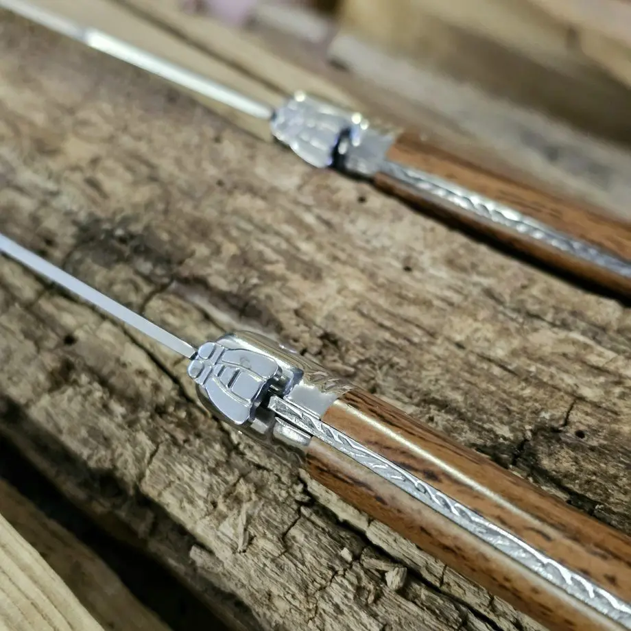 Köttknivar Laguiole Wood - 6pack köttbestick - eleganta bestick som skär snyggt kommer med vackert knivställ av trä Laguiole Wood köttknivar är lika fina att skära med som de är vackra att duka med. Du köper dessa i 6-pack och de kommer med ett vackert förvaringsställ av trä - de kan med andra ord stå framme utan att skämma ut sig. Här har du den perfekta presenten till dig själv eller en annan köttälskare som uppskattar både effektiva knivar att skära med och som gillar den eleganta och tidlösa designen som Laguiole står för. Laguiole Besticken har ett detaljerat och vackert handtag som ligger bra i handen. Handtag och knivblad har samma längd 12cm + 12cm, vilket ger knivarna en perfekt balans. Eggen är mycket fint tandad vilket gör att du utan problem skär fiber för fiber med raka snygga snitt. Dessa köttbestick bör diskas för hand även om de är klassade att tåla maskindisk (dock är maskindiskmedel ofta mer blekande och tärande på material med mycket detaljer - som dessa knivar har). I förpackningen ingår: 6 stycken eleganta Laguiole köttknivar 1 styck knivställ / knivblock i trä