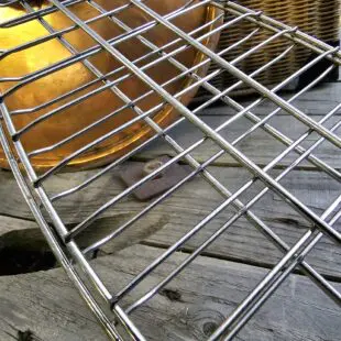 Fiskhalster Grillhalster med krok istället för handtag - passar med locket stängt - rostfritt stål Fiskhalster är ett grillhalster tänkt för hel fisk eller filéer. Fördelen blir enkel vändning utan att fisken går sönder eller bränner fast på gallret. Krok för vertikal rökning avslutar. Halstret ersätter grillnät med fördelen att du slipper teflonliknande material i din matlagning.  BBQmonsters Fiskhalster är konstruerat i formen av en fisk i storlek runt 2kg. Halstret öppnas och stängt enkelt med en ring som låser de båda sidorna. Innehållet i halstret skapa spänningen som krävs för att ringen skall låsa sig fast och utrymmet är naturligt flexibelt och tolererar en tjocklek på mellan 2 och 4 cm. Vill du grilla eller röka fisken så är det praktiskt att halstret inte har ett handtag, på så vis kan du utföra rökningen med stängt lock. Storleken gör att detta fiskhalster passar både i gasolgrillar, Kamado grillar som Kamado Joe classic och klotgrillar (och givetvis större modeller som Big Joe och offset smokers) Finns utrymmet till att hänga in fisken vertikalt är detta möjligt tack vare att halstret avslutas med en krok. För ännu säkrare förankring kan du först hänga in en slaktkrok och sen hänga halstret i denna. Fördelen med hängande rökning av fisk är att du förlänger tiden i rök, då luft leder sämre än galler (som fisken annars ligger på). Testa gärna kallröka lax och öring med en kallrökningsenhet, en spiral du fyller med spån och fjuttar fyr, utan att använda någon annan form av värmekällan.