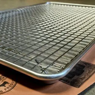 Cooling rack XL - Avsvalningsgaller - 58cm x 38cm - låt köttet vila effektivt på detta galler av rostfritt stål, skräddarsytt för våra egna aluminiumbrickor Cooling rack XL är vårt egna, extremt stabila och välbyggda avsvalningsgaller för vår största aluminium-bricka. Rostfritt stål som håller år ut och år in. Som på alla andra produkter som vi är extra stolta över bär också detta galler vår logo  - ett mynt, eller ett logo-coin som vi kallar det, fast-svetsat uppe i en hörnet. Med Cooling rack XL skapar du luft under köttet och processen med att vila ner köttet (ex. brisket eller pulled pork karré) ned mot 70 grader går därmed snabbare. Detta rack är gjort för vår största aluminiumbricka - perfekt när du preppar kött och vilar en stor brisket till perfektion.