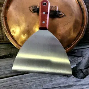 Stekbordsskrapa XL - 50% bredare Snygg och rejäl stekbordsskrapa för kolstål mm. rengör ännu enklare stekbord och stekytor på din grill och i köket Stekbordsskrapa XL- så du kan lägga in spackelspaden i förrådet igen. Perfekt för rengöring av kolstålsstekbord. Bred, stabil, vass och oumbärlig. Stekborsskrapan har en vass egg med en vinkel som gör att den håller sig vass även vid tufft arbete mot hårt underlag såsom kolstål eller gjutjärn. Handtaget är av äkta trä och har snygga nitar i rostfritt samt ett hål för upphängning på en spik eller krok.