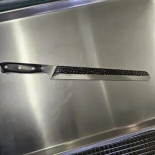 Smidd brisketkniv 43cm Skinkkniv / slicer Trancherkniv för tunna och jämna skivor Smidd brisketkniv 43cm med vackert hamrat stål på bladet vilket gör att skivorna inte limmar sig fast. Fungerar suveränt även som skinkkniv och såklart även för kallrökt lax. Här har du en mycket prisvärd smidd och bankad Brisketkniv 43cm lång, vilket når tvärsöver även en full brisket. Denna brisketkniv har ett lite över medelstyvt blad och såklart en sylvass egg. Den bankade ytan är inte bara vacker utan minskar risken för att det som du skär upp fastnar på bladet.