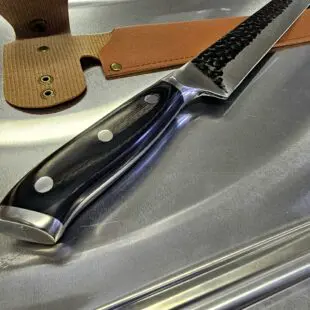 Smidd brisketkniv 43cm Skinkkniv / slicer Trancherkniv för tunna och jämna skivor Smidd brisketkniv 43cm med vackert hamrat stål på bladet vilket gör att skivorna inte limmar sig fast. Fungerar suveränt även som skinkkniv och såklart även för kallrökt lax. Här har du en mycket prisvärd smidd och bankad Brisketkniv 43cm lång, vilket når tvärsöver även en full brisket. Denna brisketkniv har ett lite över medelstyvt blad och såklart en sylvass egg. Den bankade ytan är inte bara vacker utan minskar risken för att det som du skär upp fastnar på bladet.