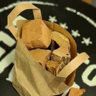 Mesquite chunks - stora bitar Rökträ, Rökved för vildsvin och tex-mex Ger en tydlig och kraftfull rök MESQUITE i detta fallet Amerikanskt trä. Mesquite är en buske, tillhörandes samma släkte av Baljväxter som exempelvis Jordnöten. Denna buske kan bli (och blir oftast) ett trä…ett rejält sådant – upp till 50 meter högt. Det kallas bland annat för “Djävulsträdet” eftersom dess djupgående rötter suger livet (vattnet) av andra växter i dess närhet. Denna egenskap är samtidigt det som gör att trädet kan växa på de mest extrema platser. På tal om djävulskt…röken är just det, djävulskt kraftig, pepprig och het. Lagom är bäst när det gäller Mesquite men du bör absolut testa att rökgrilla Kyckling över Mesquiterök. Testa även att köra en mix av Hickory och Mesquite till nötkött – kraftfullt! Flera kunder bekräftar att Mesquite är deras förstaval av rökträ för vildsvin - testa själv. Läs gärna mer om vilka träslag som kunder tycker passar bäst till olika djur och styckdelar, du läser det i BBQMonsters grillskola - här! Chunks är beskrivning av en knappt knytnävsstor träbit - en vedklabb sågad i ungefär 4 bitar och kluven 1 eller 2 gånger. Fördelen med chunks före wood chips och rökspån är att en trä-chunk inte brinner upp medans du stänger locket och tar en sipp av ölen, - detta trä kan producera rök under ett par timmar eller mer. Om du är ute efter att röka köttet och köra low & slow är det utan tvekan denna storlek du bör välja. Sikta på att tillföra rök under åtminstone de tre första timmarna. Det är då som köttet är som mest mottagligt för rök. Faktum är att det framför allt är när köttet är riktigt kallt (eller fruset) som mest rökpartiklar fastnar på ytan (testa till exempel att röka lax frusen!). När köttet blir torrt på ytan slutar köttet till stor del att ta emot röken. Det är i detta läget som det kan vara aktuellt att använda en sprayflaska för "slather" (se denna artikel) Levereras i en fullpackad pappåse om 6liter (vikt varierar beroende på träslag men ca 1,8kg) Om att använda trä för att skapa rök: Blött trä släcker delvis glöden från kolen och skapar oftast en smutsigare rök. Målet när du tillför rökträ är att skapa en fullständig förbränning där röken är klar och fin, inte tjock och mullrande. Thin blue smoke pratar det stora landet i väster om och även om det inte alltid är blå rök som lämnar skorstenen så kan du ha det i bakhuvudet: mörk rök är dåligt, vit rök är bättre men inte bra, ljus eller blåskimrande rök är frisk rök och ger bäst smak och doft. Om du upplever att röken inte är ljus kan du testa att öppna spjällen något mer och på så sätt förbättra förbränningen. Var dock noggrann med att se till att temperaturen inte rusar iväg. När du kör low & slow kan det vara idé att sprida ut 3-6 chunks över kolen så att rök tillförs under hela sessionen, börja med att lägga den minsta biten (eventuellt kluven till stickor) direkt där du tänt kolen, på så sätt startar rökutvecklingen med en gång. Kom ihåg: Torrt trä, med eller utan bark Använd bara trä som du gillar doften från Ljus, klar rök (öka luftflödet om det behövs)