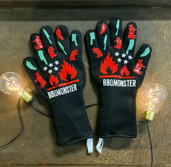 Grillvantar - BBQ gloves Uppdaterad design - nya motiv och ännu längre skaft! Grillhandskar - BBQ Gloves - Värmetåliga Handskar - skyddar bättre än läder! Grillvantar, BBQ gloves, BBQ-handskar, Värmetåliga handskar - Ett måste för Kamado-ägaren eller den som tröttnat på grilltången. Detta är ett par Grillvantar, BBQ gloves, BBQ-handskar, Värmetåliga handskar som älskas av kunderna. Inte bara rackarens snygga utan också smidiga, bekväma och inte viktigast av allt - värmetålig utsida som tåler upp till 500 grader C. Fodret är mjuk och bekvämt och framförallt är det fastsytt så att du inte står där med en handske ut-och-in stup i kvarten. Silikonmönster på båda sidorna förbättrar greppet och passar oavsett vilken handske som dina händer glider in i.  Extra långa Grillvantar, BBQ gloves, BBQ-handskar, Värmetåliga handskar (33 cm) vilket ger dig skydd en bit upp på underarmarna - något som inte minst alla som gjort smash-burgers på ett hett stekbord kan förstå att uppskatta. Använd Grillvantar, BBQ gloves, BBQ-handskar, Värmetåliga handskar för att flytta galler, deflektorstenar etc. Priset är för ett par (alltså 2 stycken handskar) Grov rejäl kvalitet Extra långa (skyddar handlederna) Tvättbara i maskin OBS: väta försämrar värmeskyddet, används torra. Om du skall transportera heta objekt under längre stunder i sträck kommer handsken bli uppvärmd oavsett hur bra värmeskyddet är, handskarna är gjorda för att utsättas för värme under kortare stunder åt gången. Storleken är rejält tilltagen för att passa alla (okej - är du svartsmed med svullna händer så kan det bli tight men annars...).