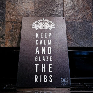 Plåtskylt / Tin sign med budskapet: keep calm and Glaze the ribs. Given vid grillen eller uteköket Skylt för kök, utekök, grillhörna, BBQ, Bar, Mancave Dekorera din favoritplats med skyltar och metalltavlor En tavla med de bevingade orden "Keep calm and glaze the ribs" Ja, är ju avslappnande, så varför inte? En perfekt skylt att hänga vid din favoritplats. När du lägger på glaze på revbenen kan denna vara till hjälp Tin signs: Tavlor i metall och plåtskyltar? BBQmonster har en häftig samling tavlor och skyltar i metall som kan vara den perfekta presenten eller tillbehöret till presenten som gör pricken över i:et, eller "the prick over the eye" som man säger i Amerikat... Metalltavlor för grill och BBQ är efterfrågade dekorer till utekök, mancaves och grillhörnor och med BBQmonsters uppsättning är chansen god att du hittar en skylt som passar just dig eller den person du skall köpa presenten till. Ett presenttips kan vara att om du köper låt säga ett paket spanska ginglas att då komplettera med en skylt som förstärker budskapet. Samma sak kan appliceras Ölglas, Kamados osv. Livsnjutare, Foodies och grillare är ofta glada för både god mat och god dryck. Därför kretsar många av dessa vintage skyltar och metalltavlor på tema Mat, såsom recepttavlor (för exempelvis Pulled pork, Revben / Ribs och Brisket). Eller Dryck (whisky, bourbon, beer, öl, IPA, Cider, Stout och inte minst modedrycken GIN). Tavlorna i metall finns i ett antal olika format, men där det vanligaste är måtten 20 x 30 (stående) cm eller 30 x 20 (liggande). Det finns även ett par större modeller (bland annat runda). Skyltarna har en vikt kant så inga vassa kanter existerar. Hörnen är försedda med hål (på det fyrkantiga tavlorna) där du enkelt med två eller fyra spik eller skruvar fäster upp tavlan på underlaget. Du kan även använda dubbelhäftande tejp om det passar bättre mot underlaget. Keep calm and glaze the ribs! Du hittar alla tavlor och skyltar under kategorin Tavlor metall (www.bbqmonster.se/produkt-kategori/tavlor/)