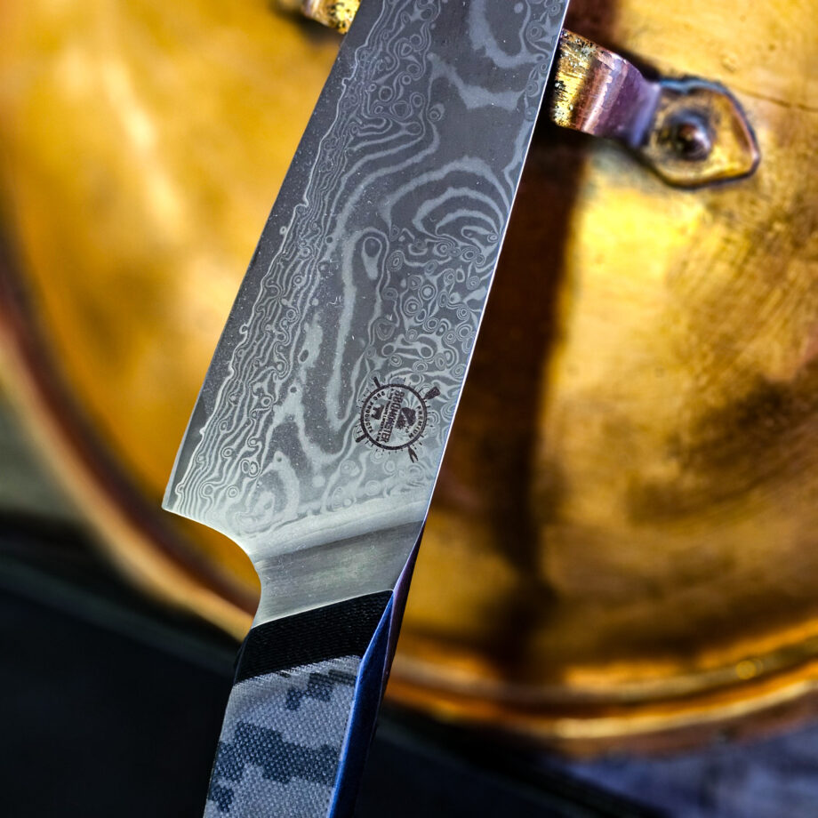 Kockkniv "Camo36 #1" - den längsta i BBQmonsters finaste knivserie. Rakbladsvasst blad med vacker damaskus mönster och coolt digi-camo-handtag En smidig, lättstyrd och inte minst vacker kockkniv - Camo36 #1 Introduktionspris - passa på! Bladet är vackert damaskusmönster - som helhet en av de vackraste knivar som vi sett och definitivt den vassaste - totalt 100% "intstagramvänlig" och photogenique. Vi gjorde ett test med denna kniv: en liten plommontomat (ca 10 gram) släpptes från några decimeters höjd mot knivens egg och utan att studsa så skars tomaten i en fin skiva med endast tyngdlagens inverkan mot knivens egg - imponerande! Ibland kan man se liknande test men där man istället släpper något betydligt tyngre, som en mindre melon eller en banan...ett sådant test säger inte allt för mycket, men vårt test berättar att denna kniv skall behandlas med största försiktighet. Denna kockkniv är en perfekt present, julklapp eller farsdagspresent till dig själv eller någon annan som uppskattar matlagning. Kniven levereras i en svart presentbox med BBQmonsters logo och sigill. Total längd: 36 cm Längd på bladet: 23 cm Längd på skaftet: 13 cm Vi rekommenderar att du använder våra smidiga skyddshandskar när du använder denna kniv