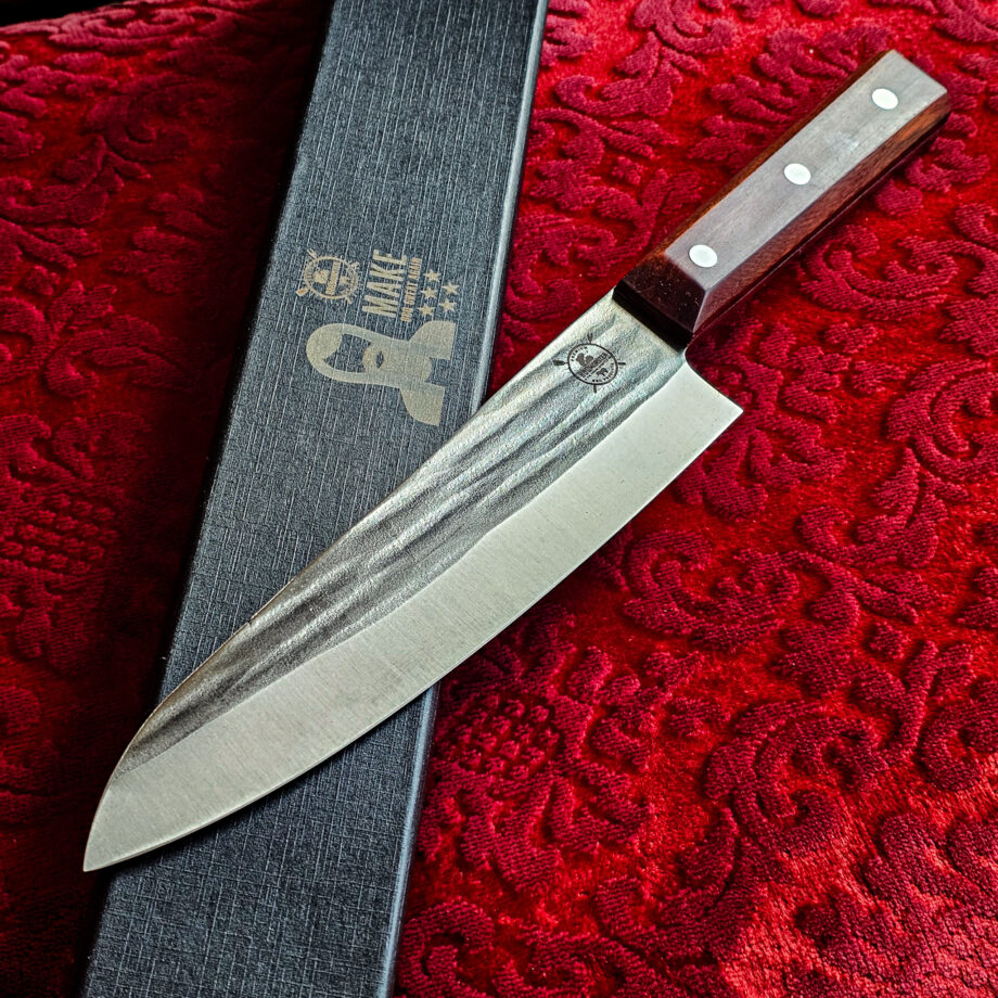 Gyuto Kockkniv Red Velvet #14 vacker kockkniv från BBQmonsters serie av Asiatiska kockknivar - liknande kniv säljs för det tredubbla på andra sidor! Söker du en serie av välarbetade och lättskötta kockknivar? Ta en kik på BBQmonsters egna serie knivar! Samtliga knivar i serien kommer i en svart presentförpackning med BBQmonsters sigill "Make BBQ great again" tryckt på locket. Knivarna från BBQmonster har även BBQmonsters logo ingraverad på bladet. Vi sätter bara vår logo på prylar som vi verkligen tycker om - detta är en sådan. Introduktionspris - passa på! En perfekt till grillnörden, en present till pappa på farsdag eller till dig själv helt enkelt! Gyuto kockkniven i serien Red velvet är i det närmsta du kommer en klassisk europeisk kockkniv när det gäller asiatiska knivar. Detta är alltså en kniv som kan användas för både kött och grönsaker. Det är enkelt både att skära raka skivor av en stek och med en gungande rörelse hacka örter och grönsaker till mindre delar. Bladet på denna Red Velvet #14 är vackert dekorerat med mjuka följsamma mönster inhamrat i stålet. Bladet har en perfekt balans mellan smidigt och robust. Eggen är extremt vass och lättskött. Varje blad är unikt i sitt utseende vilket tillsammans allts som allt gör detta kniven rejält "intstagramvänlig" och photogenique. Bladet är genomgående och avslutas med det snygga fyrkantiga handtaget som är av rött ädelträ och som har tre nitar av mässing. Skaftet ger ett skönt grepp och är enkelt att rengöra. Handtaget passar både höger- och vänsterhänta. Kolstål med blandning X50CrMoV15 Hårdhet 56° HRC vilket är ett relativt mjukt stål - något som gör att du själv enkelt kan hålla din kniv vass. Total längd: 33 cm Längd på bladet: 20 cm Längd på skaftet: 13cm Vikt: 246 gram