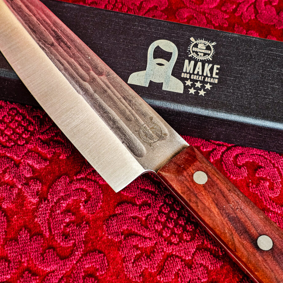 Santoku kockkniv Red Velvet #16 vacker kockkniv från BBQmonsters serie av Asiatiska kockknivar - liknande kniv säljs för det tredubbla på andra sidor! Söker du en serie av välarbetade och lättskötta kockknivar? Ta en kik på BBQmonsters egna serie knivar! Samtliga knivar i serien kommer i en svart presentförpackning med BBQmonsters sigill "Make BBQ great again" tryckt på locket. Knivarna från BBQmonster har även BBQmonsters logo ingraverad på bladet. Vi sätter bara vår logo på prylar som vi verkligen tycker om - detta är en sådan. Introduktionspris - passa på! En perfekt till grillnörden, en present till pappa på farsdag eller till dig själv helt enkelt! Santoku betyder "tre syften" på japanska och det berättar att detta är en kockkniv för både fisk, kött och grönsaker. Det lite kortare bladet gör att det är enkelt att arbeta med precision. Behöver du ett längre blad för att tranchera större stekar så ta en kik på Gyuto varianten i denna Red velvet serie. Bladet på denna Red Velvet #16 är vackert dekorerat med mjuka följsamma mönster inhamrat i stålet. Bladet har en perfekt balans mellan smidigt och robust. Eggen är extremt vass och lättskött. Varje blad är unikt i sitt utseende vilket tillsammans allts som allt gör detta kniven rejält "intstagramvänlig" och photogenique. Bladet är genomgående och avslutas med det snygga fyrkantiga handtaget som är av rött ädelträ och som har tre nitar av mässing. Skaftet ger ett skönt grepp och är enkelt att rengöra. Handtaget passar både höger- och vänsterhänta. Kolstål med blandning X50CrMoV15 Hårdhet 56° HRC vilket är ett relativt mjukt stål - något som gör att du själv enkelt kan hålla din kniv vass. Total längd: 30,5 cm Längd på bladet: 17,5 cm Längd på skaftet: 13cm Vikt: 234 gram