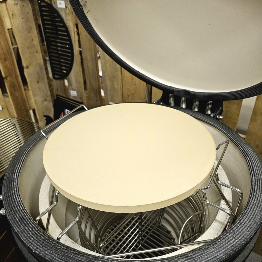 Pizzasten - 38cm i diameter Hela 2cm tjock (33% tjockare än de flesta andra) = bättre värmefördelning Inkluderar en hållare (handtag) i metall för enklare hantering av en varm sten Pizza på pizzasten är hemligheten till en "köp-pizza-känsla" där degen är krispig och genombakad utan att blivit som ett knäckebröd. Denna pizzasten är gjord av högkvalitativ värmetålig keramik. Passar både i klotgrillar (som weber 57), gasolgrillar, ugnar och såklart kamado såsom kamado Joe, bastard kamado, Big green egg, sumo mfl. Denna pizzasten har en diameter på 38 cm, vilket är en alldeles lagom storlek på en pizzza - större och det blir svårt att göra annat än Calzone... Pizzastenen är hela 2cm tjock vilket är ungefär 33% tjockare än de flesta pizzastenar och tjockleken är inte oviktig - tjockare sten ger en bättre värmefördelning och mindre risk för en bränd pizzabotten. Många är vi som på början av 2000 talet letade efter det perfekta receptet på pizzadeg i tron att detta var skillnaden som gjorde skillnaden - vi hade FEL. Hemligheten till en bra bakad pizza ligger istället i att degen bakas under ifrån, från ett redan hett underlag - alltså en upphettad pizzasten. Lagom temperatur i grillen (eller ugnen) är 280 till 350 grader. För många är det då grillen som gäller, då de flesta hushållsugnar stannar på runt 225grader. Tekniken är: varm upp stenen, kavla ut degen på ett bakplåtspapper, dressa din pizza med dina favoriter men börja alltid med tomatsåsen, därefter pizzaosten, sen är det valfritt. Lyft över pizzan på sitt papper, låt den landa på stenen och ganska snart kan du rycka bort pappret. Använd pizzaspade (artikel nr 31016) för att lyfta bort pizzan när osten bubblar. Diameter 38 cm Skydda tassarna med värmetåliga handskar